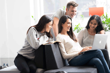 Jovenes universitarios sonriendo frente a un computador