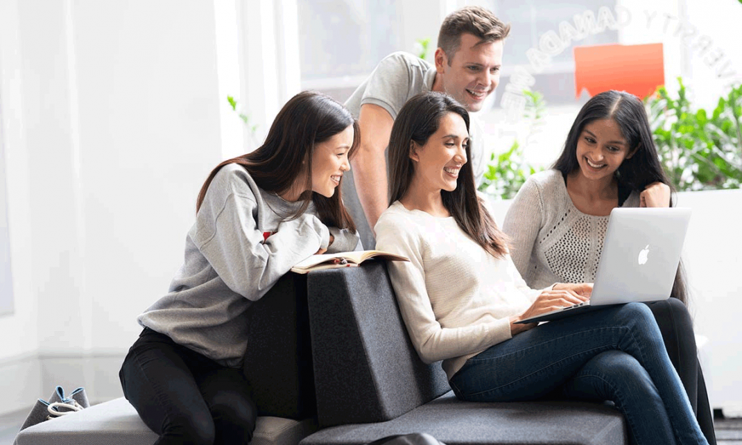 Jovenes universitarios sonriendo frente a un computador